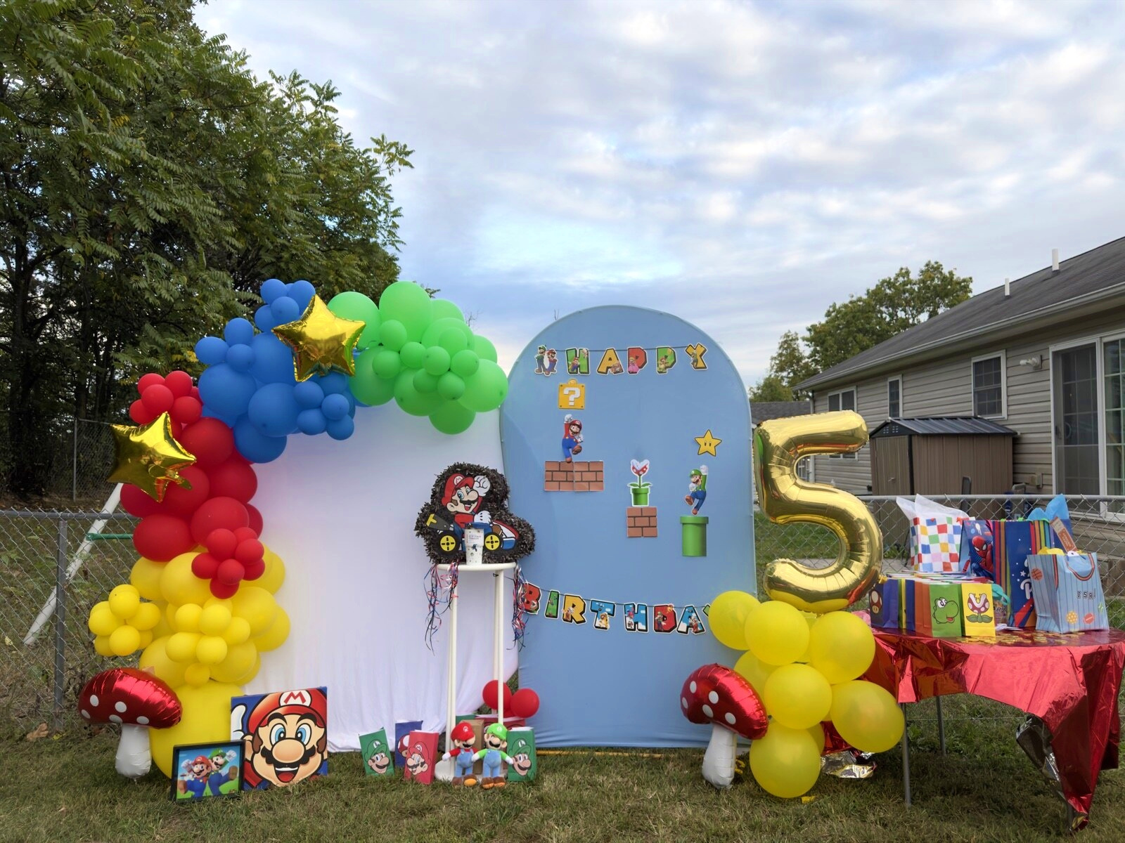 Isaiah Level 5 party backdrop: balloon arch, blue panels and a gold number five