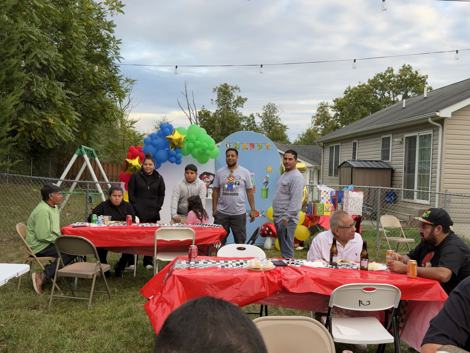 Guests standing by the birthday backdrop behind a red table