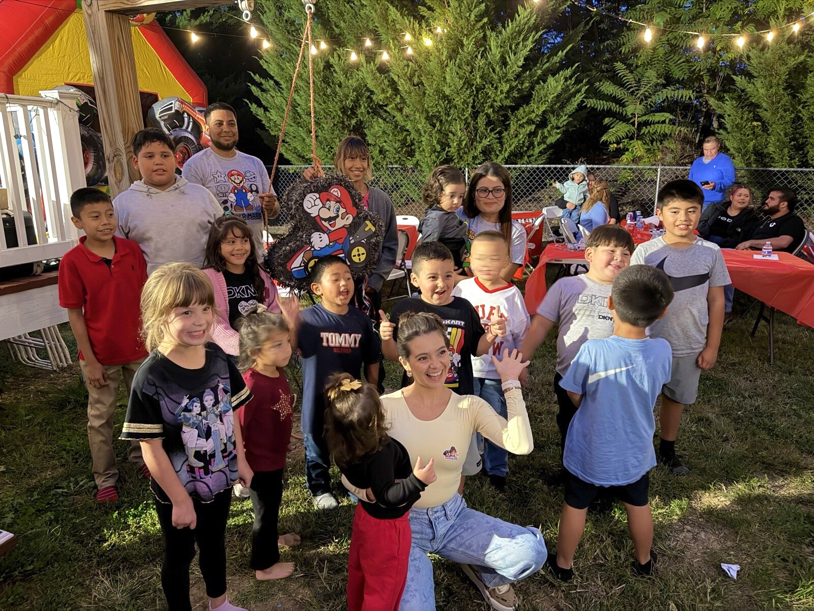 A group gathering around a piñata under warm string lights