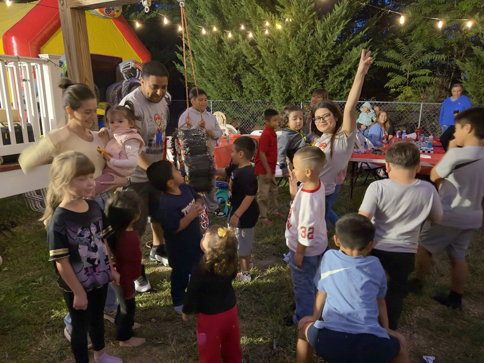 Guests raising their arms near the piñata in the evening